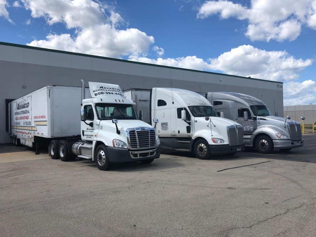 moving trucks parked outside a warehouse for storage and relocation services.